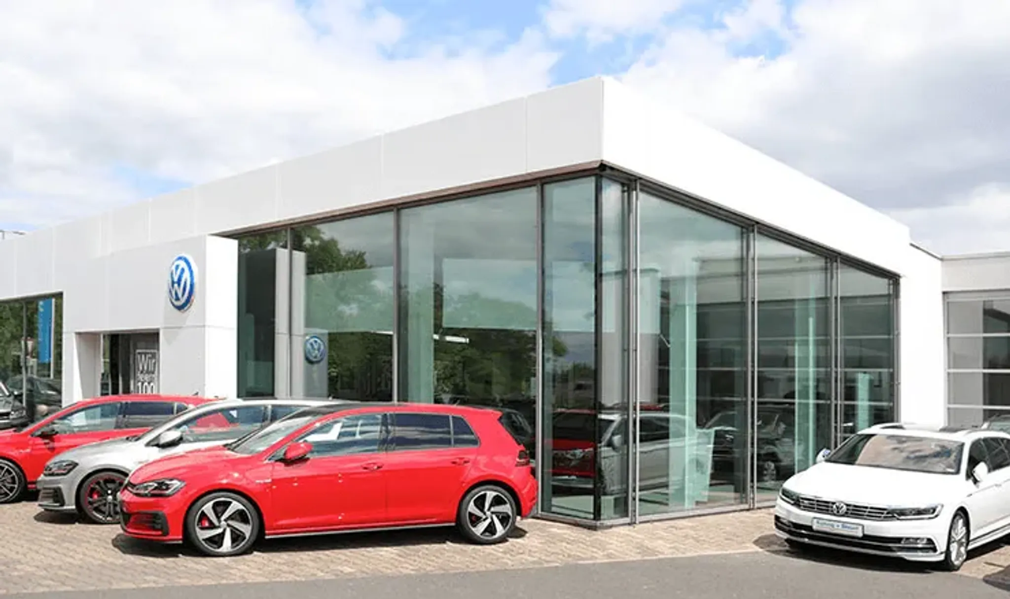 Golf in rot vor einem Autohaus mit verglaster Front