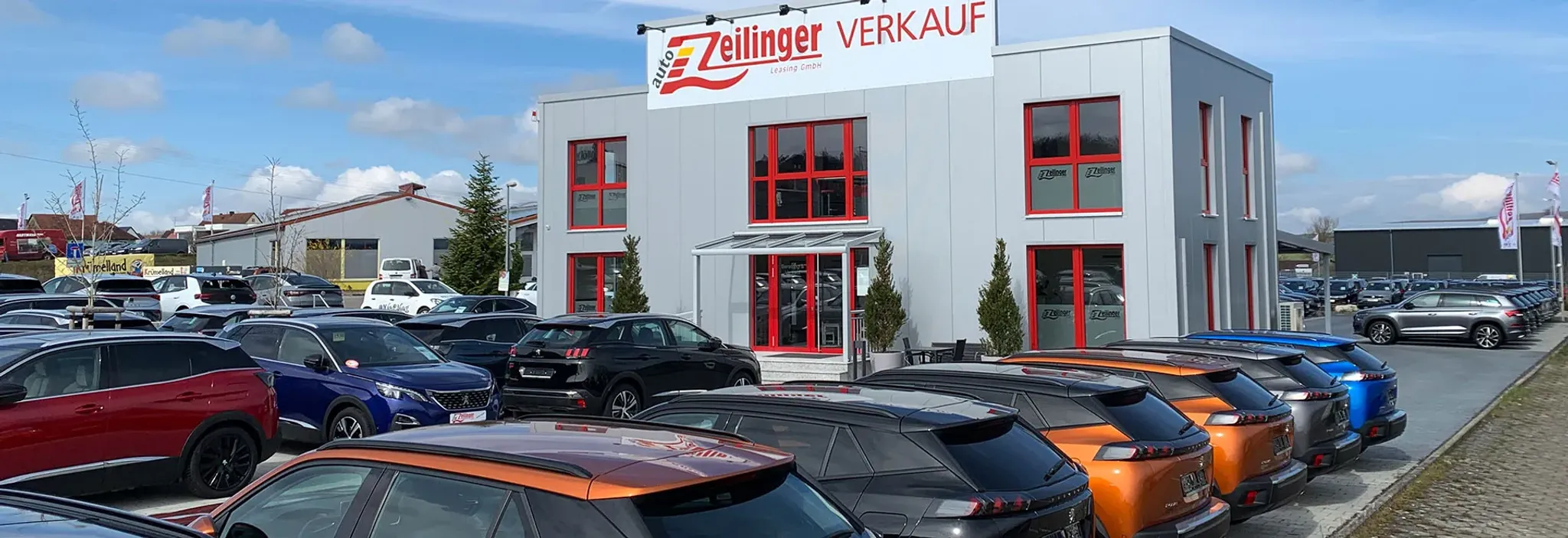 Verschiedene Fahrzeuge in einer Reihe, vor dem Autohaus Zeilinger Verkaufsgebäude diese steht im Fokus